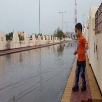 طفل على رصيف شارع ممتلئ بمياة الامطار